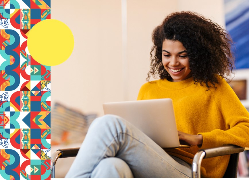 Foto de una mujer sentada trabajando con un portátil y sonriendo