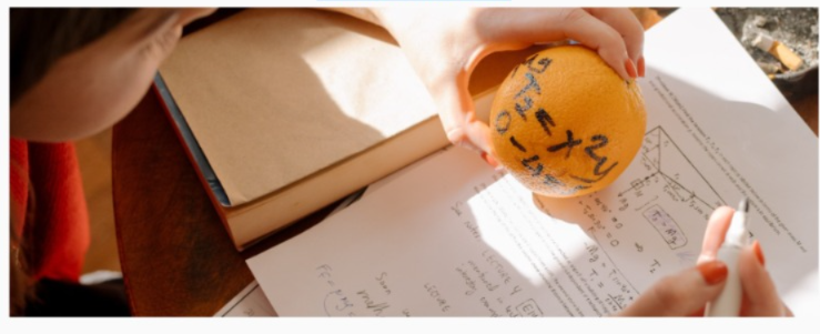 Niño sostiene una naranja la cual tiene ecuaciones matemáticas escritas  