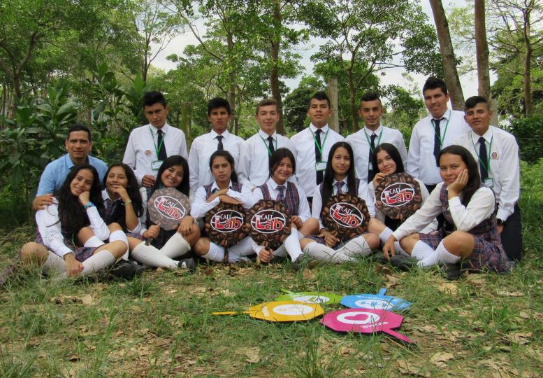 Grupo de estudiantes de institución Montessori, con profesor Maje, sostienen una paleta que dice "Cafelab"