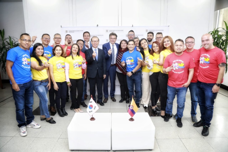 Foto de los docentes becarios a Corea del Sur con el Ministro Alejandro Gaviria, en un salòn con las banderas de Corea del Sur y Colombia