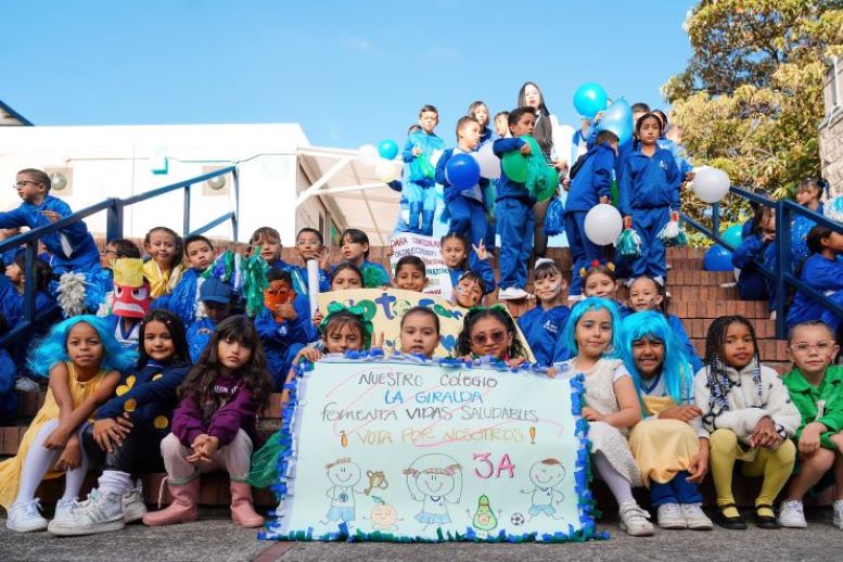 muchos niños y niñas con uniforme sentados en las gradas de una escuela