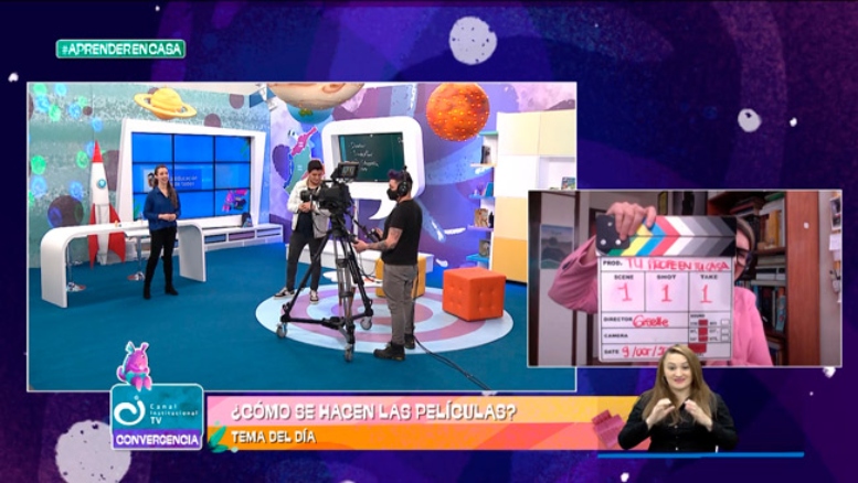 Presentadores hombre y mujer en estudio de televisión, con camarógrafo y escenografía de planetas; una claqueta anunciando la primera escena; la foto de la intérprete de señas