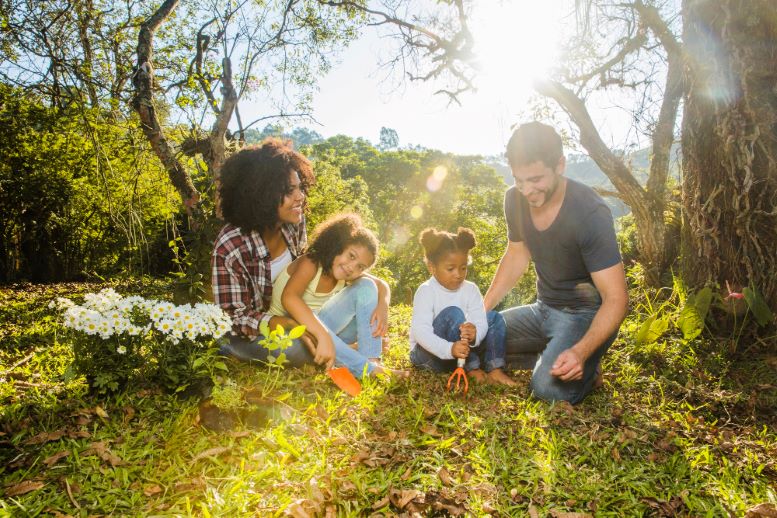 Familia compuesta por padre, madre y dos niñas, disfrutan del campo y cortan margaritas