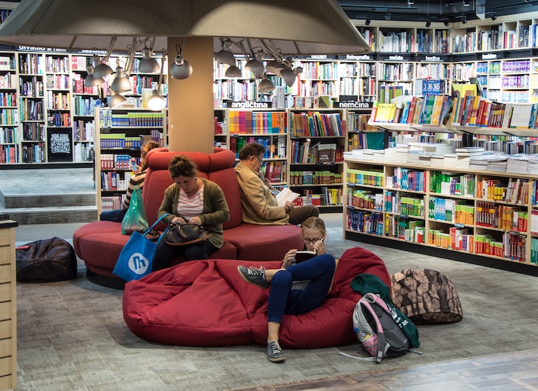 Foto de varias personas sentadas en una librería leyendo