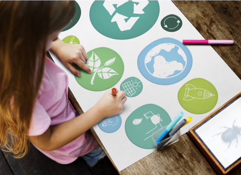 Concepto de educación sobre el niño y el medio ambiente. Niña dibuja cartelera con simbolos alusivos a la educación ambiental