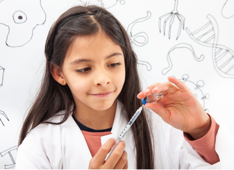 Una niña mira con detenimiento una probeta de laboratorio