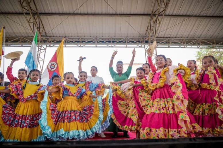 Grupo de niños y niñas en traje de baile y detrás la ministra de educación y el profesor Maje levantan las manos