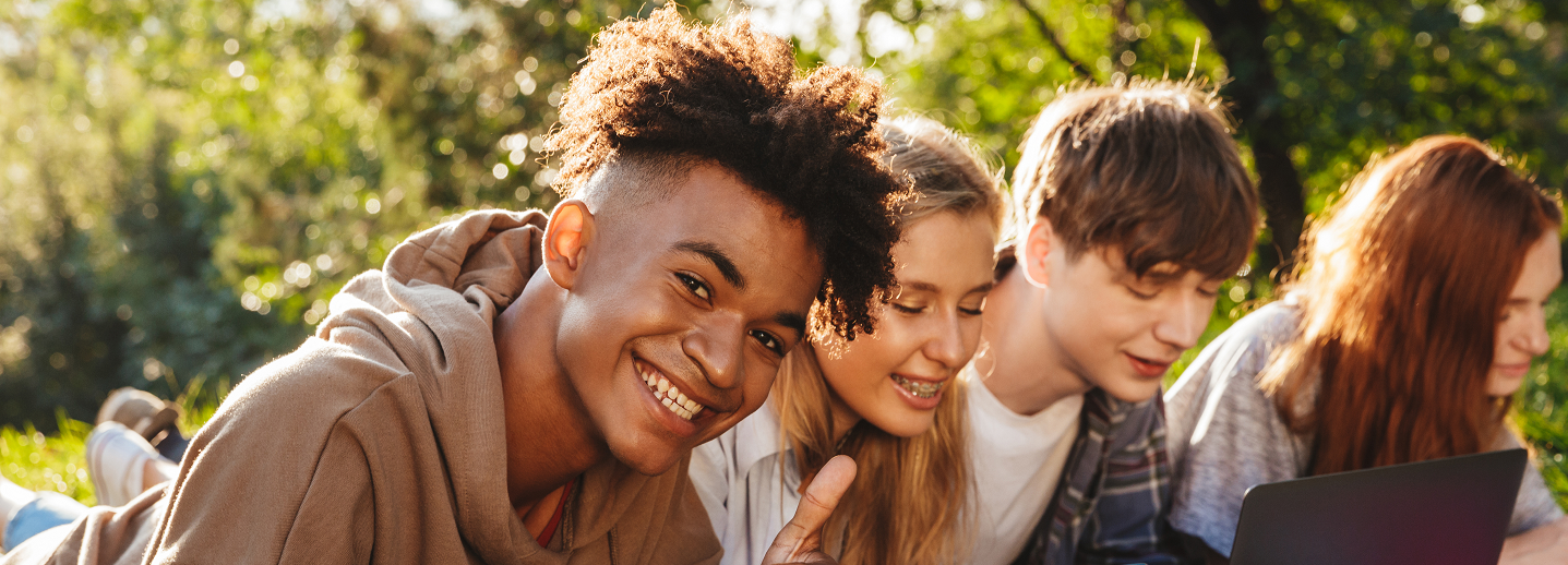 Foto de niños sonriendo con un computador en un parque