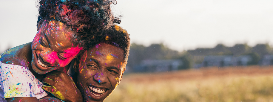 Mujer y hombre sonriendo con la cara pintada de varios colores