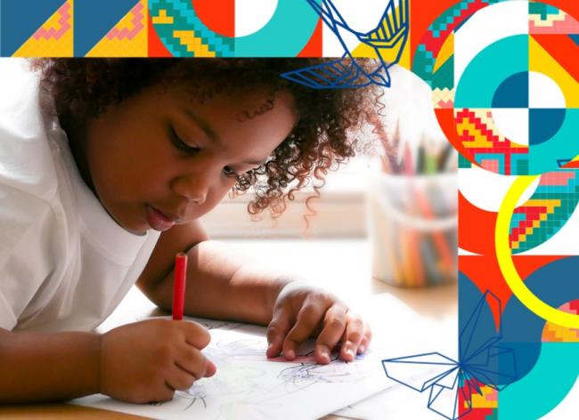 Foto de un niño estudiando con colores al lado