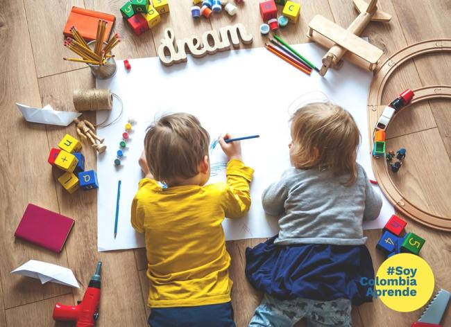 Niño y niña pequeños escribiendo con lápices de colores sobre una cartelera