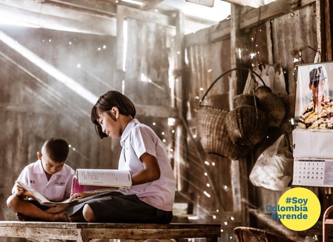 Niños estudiando con luz natural dentro de una casa de madera