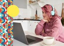 Foto de una mujer en escritorio frente a computador con un café sobre la mesa y unos audífonos puestos